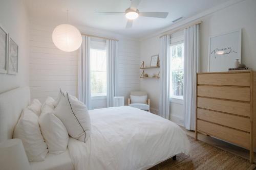 a white bedroom with a bed with white pillows at Villa Marguerita by WB Abodes in Wrightsville Beach