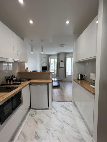 - une grande cuisine avec des placards blancs et un sol en marbre dans l'établissement Stylish apartment in Paris, à Paris
