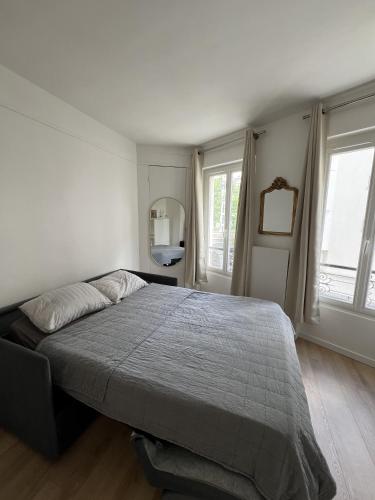 une chambre avec un grand lit et deux fenêtres dans l'établissement Stylish apartment in Paris, à Paris