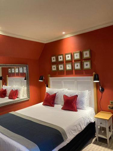 een slaapkamer met een groot bed met rode muren bij Hotel Manor - Datchet, Windsor in Datchet