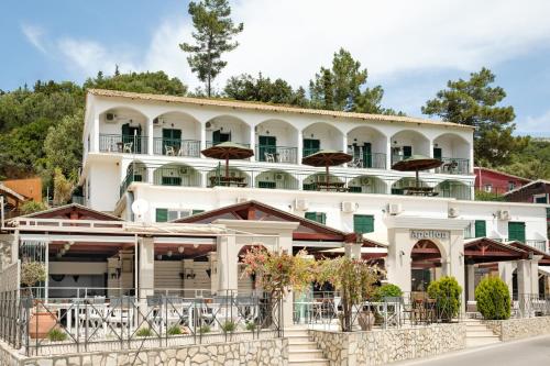 um grande edifício branco com guarda-chuvas em Hotel Apollon Corfu em Paleokastritsa