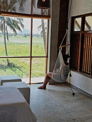 a person sitting in a hammock in a room at Linwewa Villa, Sigiriya in Sigiriya