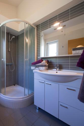 a bathroom with a shower and a sink and a tub at Apartmani Villa Athina in Tučepi