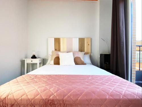 1 dormitorio con 1 cama grande y edredón rosa en Las Barajas de Saturno en Madrid
