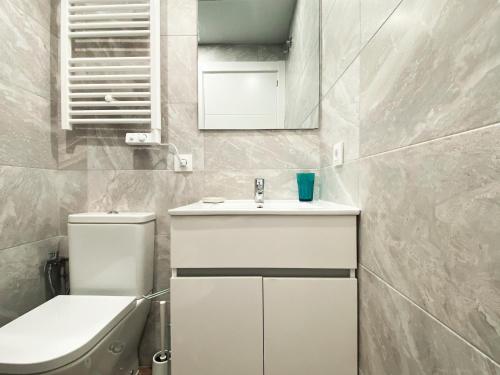 W łazience znajduje się umywalka, toaleta i lustro. w obiekcie Las Barajas de Saturno w Madrycie