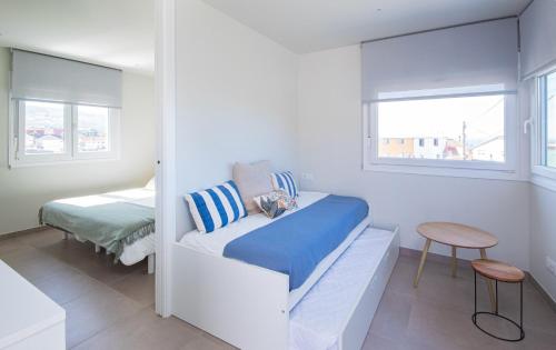 Kleines weißes Zimmer mit einem Bett und einem Tisch in der Unterkunft AG Casa do Ramon en Playa Razo con patio exterior in A Coruña
