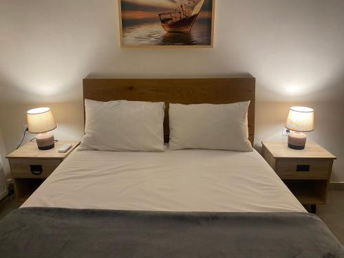 a bedroom with a bed with two lamps on tables at lividio apartment in Lefkada