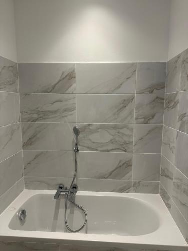 La salle de bains est pourvue d'une baignoire blanche avec un tuyau. dans l'établissement STUDIO REFAIT A NEUF CENTRE DE NICE, à Nice