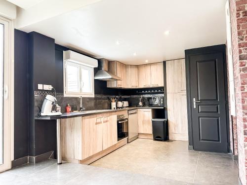 une cuisine avec des placards en bois et une porte noire dans l'établissement Anh K - TiamConciergerie - DISNEY - Meaux Centre, à Meaux