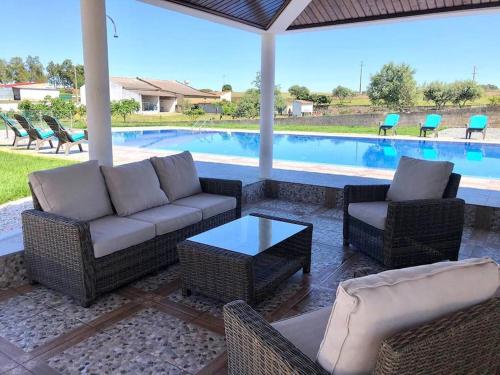 a patio with a couch and chairs and a pool at Quinta dos Sonhos in Aldeia dos Fernandes