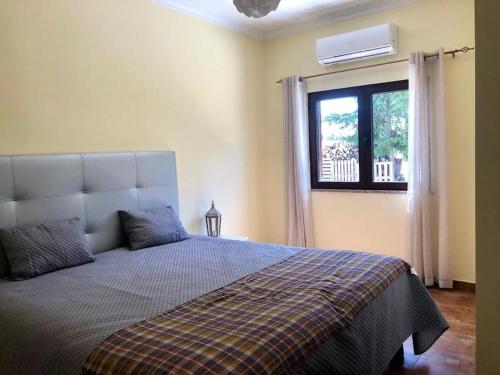 sypialnia z łóżkiem i oknem z klimatyzacją w obiekcie Quinta dos Sonhos w mieście Aldeia dos Fernandes