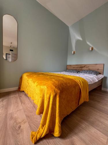 a bedroom with a bed with a yellow blanket on it at Ozolu apartment in Liepāja