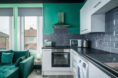 a kitchen with a stove top oven next to a couch at Social Media Adventure - 3 Bedroom - City Centre - Doncaster in Balby