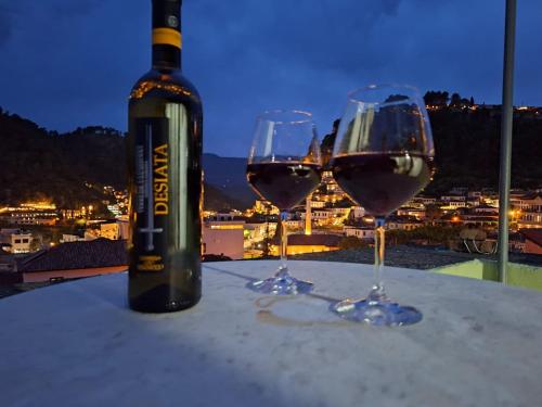 een fles wijn en twee wijnglazen op een tafel bij Guesthouse "PELIVANI" in Berat