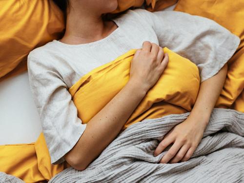 a woman laying in bed with a yellow pillow at بنك الاتحاد in Nāţifah