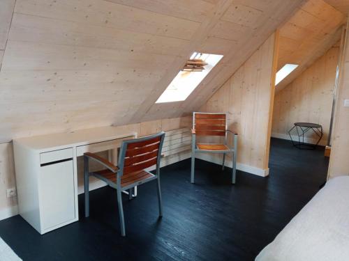 um quarto com uma secretária e 2 cadeiras num sótão em Chez Fanch em Lampaul