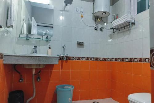 baño con lavabo y azulejos de color naranja y blanco en Hotel Snow Crest Inn - Natural landscape Mountain View en Dharamshala