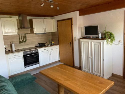 cocina con armarios blancos, mesa y TV en Ferienwohnung auf dem Erlebnisreiterhof Kreipl en Grattersdorf