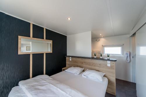 Schlafzimmer mit einem weißen Bett und einem Spiegel in der Unterkunft Holiday Village Knokke in Knokke-Heist