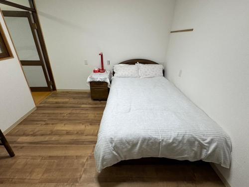 1 dormitorio con 1 cama grande y suelo de madera en Guesthouse Atelier Ten 民泊アトリエ天, en Osaka