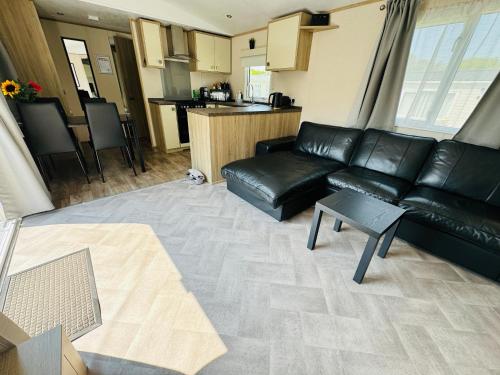 ein Wohnzimmer mit einem schwarzen Ledersofa und einem Tisch in der Unterkunft Rosa - Bournemouth Holiday Home in Wimborne Minster