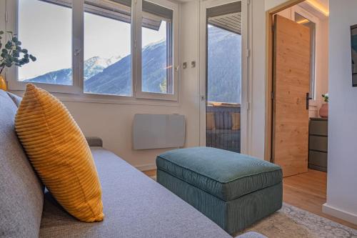 - un salon avec un canapé, une chaise et des fenêtres dans l'établissement Chamois Blanc Rosières- bright 1 bed apartment with amazing views, à Chamonix-Mont-Blanc