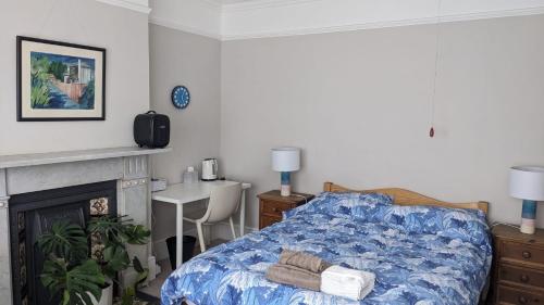 1 dormitorio con cama, mesa y chimenea en Comfort and Convenience double with ensuite London W7 en Londres