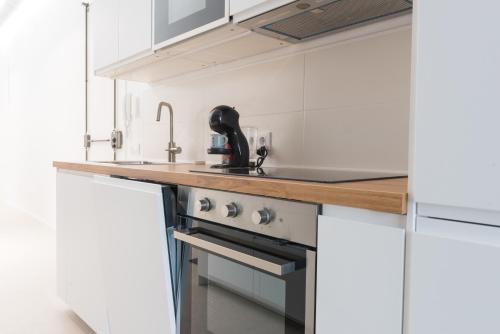 a kitchen with white cabinets and a stove top oven at Apartamento Barcelona centro in Barcelona