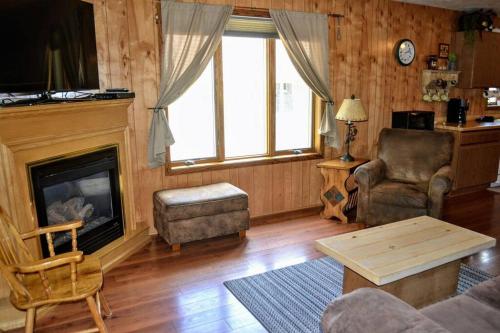 Una sala de estar con un sofá y una chimenea. en Nitschke's Resort Cabin #15, en Minocqua