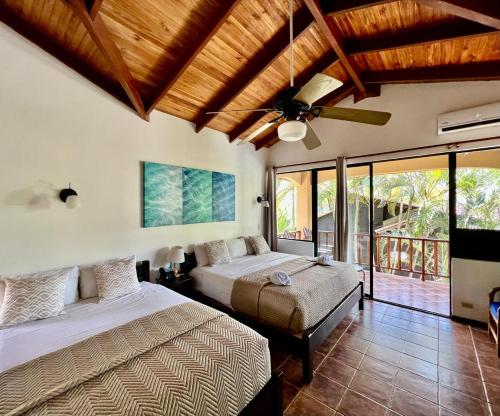 1 dormitorio con 2 camas y ventilador de techo en The Backyard Beachfront Hotel, en Jacó