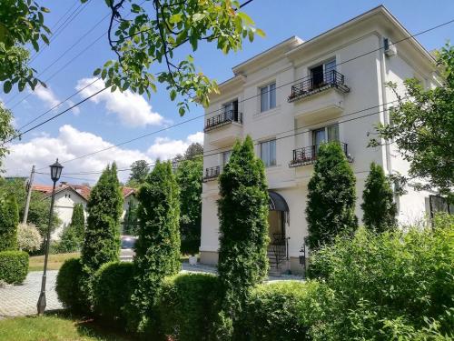 een wit gebouw met bomen ervoor bij Villa Otava Lux SPA in Vrnjačka Banja