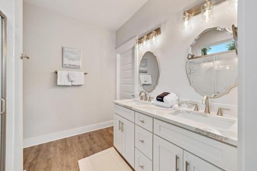 a white bathroom with a sink and a mirror at The Perdido Cottage in Pensacola