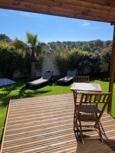 a wooden deck with a table and a chair on it at Chambre d’hôte indépendante in Lacanau
