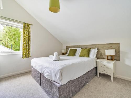 a bedroom with a large bed and a window at Rowan - Woodland Cottages in Bowness-on-Windermere