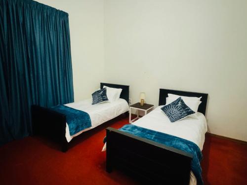 2 camas en una habitación con cortinas azules en StoneWall Villa en Mbabane