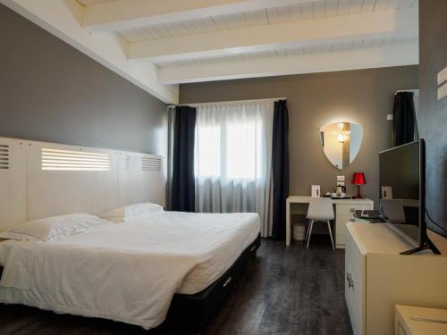 a bedroom with a bed and a desk and a television at Daytona Business Hotel in Collecchio