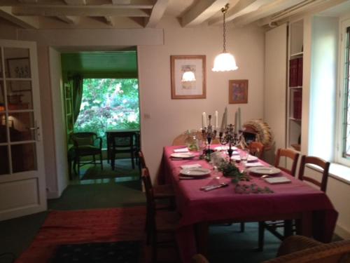 une salle à manger avec une table avec une nappe rouge dans l'établissement cottage à bethemont la foret, à Béthemont-la-Forêt