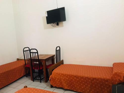 Cette chambre comprend 2 lits, une table et une télévision. dans l'établissement Hotel Piamonte, à Buenos Aires