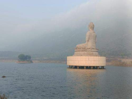 eine große Statue in der Mitte eines Wasserkörpers in der Unterkunft Nikunj Dorme in Rajgir