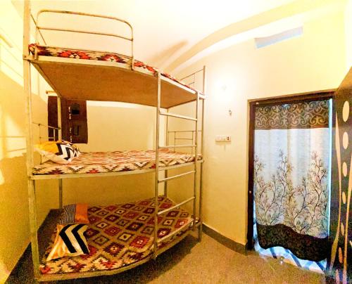 2 Etagenbetten in einem Zimmer mit Fenster in der Unterkunft Nikunj Dorme in Rajgir