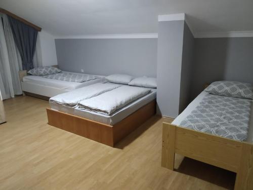 two beds in a room with wooden floors at Apartment Edin in Bihać
