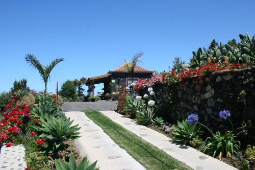 einen Garten mit Blumen und einer Steinmauer in der Unterkunft Fide in Tijarafe