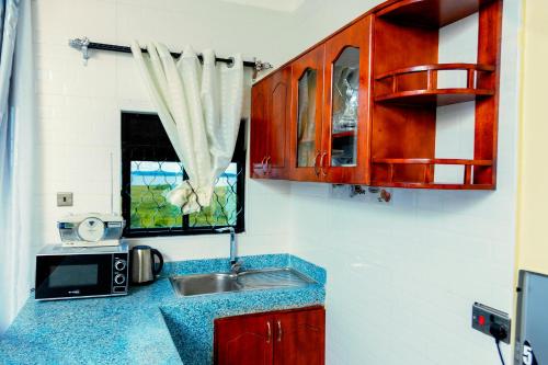 a kitchen with a sink and a microwave at Orchard apartment in Mutungo