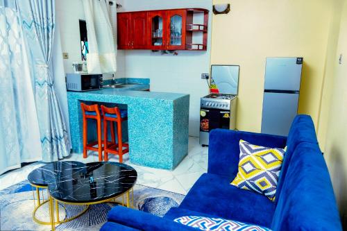 a living room with a blue couch and a kitchen at Orchard apartment in Mutungo