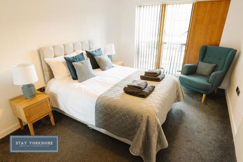 a bedroom with a large bed and a blue chair at Stay Yorkshire City Centre Apartments in Sheffield