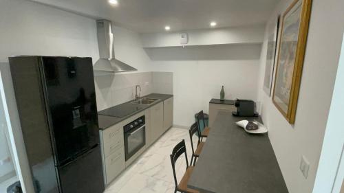 Il comprend une cuisine équipée d'un réfrigérateur noir, d'une table et de chaises. dans l'établissement Rez de villa golfe de lava, à Appietto