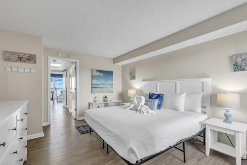a bedroom with a white bed with a teddy bear on it at Boardwalk Resort 537 in Myrtle Beach