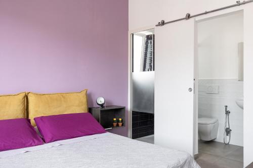 ein Schlafzimmer mit einem Bett mit lila und gelben Kissen in der Unterkunft Freshwater Pirates in Gaeta