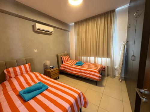two beds in a hotel room with orange and white stripes at Paez Villa in Protaras