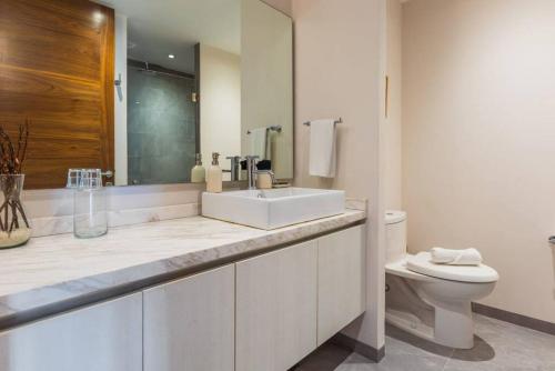 Baño blanco con lavabo y aseo en Luxury 2-bed Apartment 200MB Wifi Sauna AC Gym en Playa del Carmen